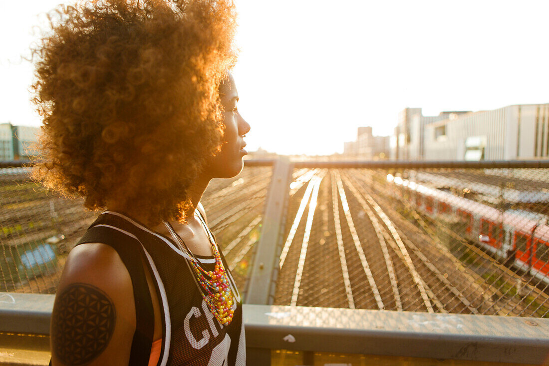 Junge afroamerikanische Frau im Gegenlicht mit Bahnhof und Gleisen, Hackerbrücke, München, Bayern, Deutschland