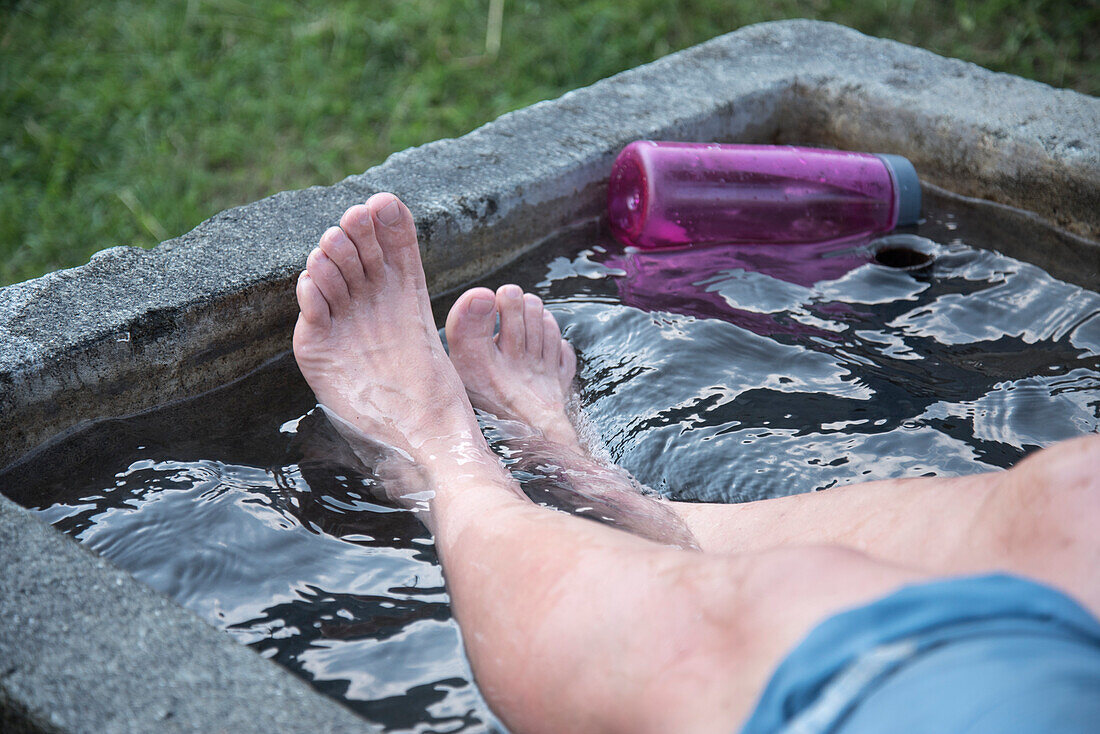 After 1600 m ascent to and 1500 descent from the Vorder Glärnisch it feels good to cool the feet, fountain in Schwändi, canton of Glarus, Switzerland