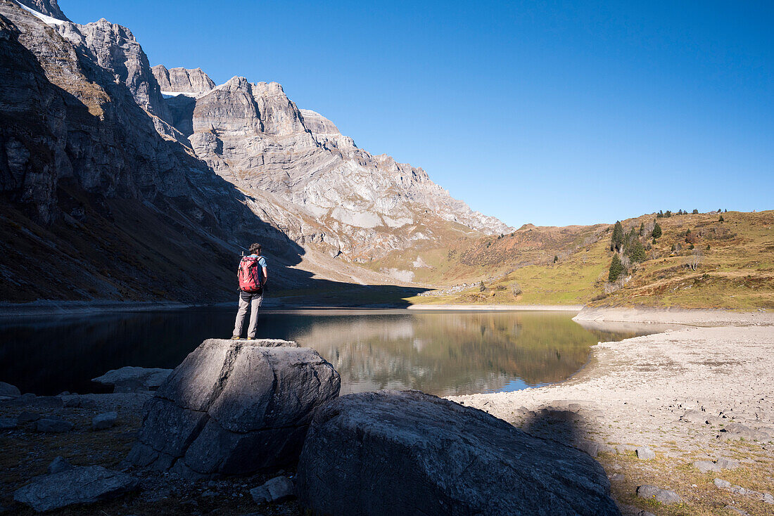 A hiker on the shore of the mountain lake Oberblegisee, Glarus Alps, canton of Glarus, Switzerland