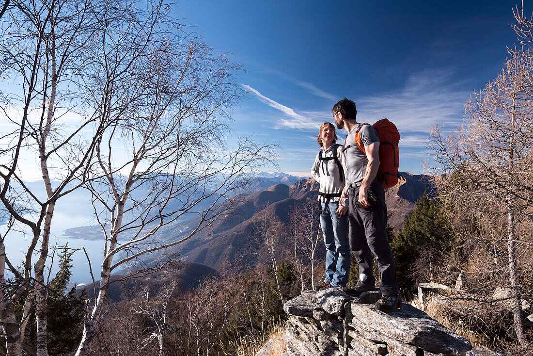 Ein Paar steht auf einer Steinmauer in der Nähe des Gipfels Sassariente in der Nähe von Bellinzona und Locarno, Lepontinische Alpen, Kanton Tessin, Schweiz