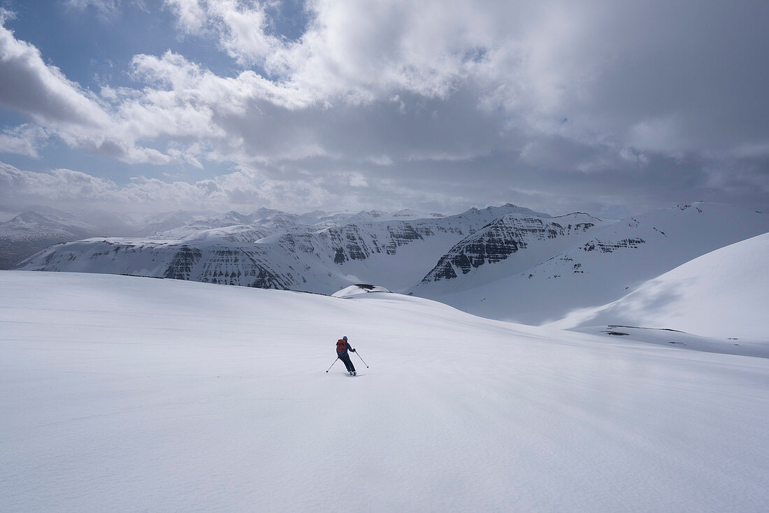 A female skitourer skiing dow the slopes of Saudaneshnjúkar near Dalvík, Tröllaskagi or in English Troll Peninsula, Iceland