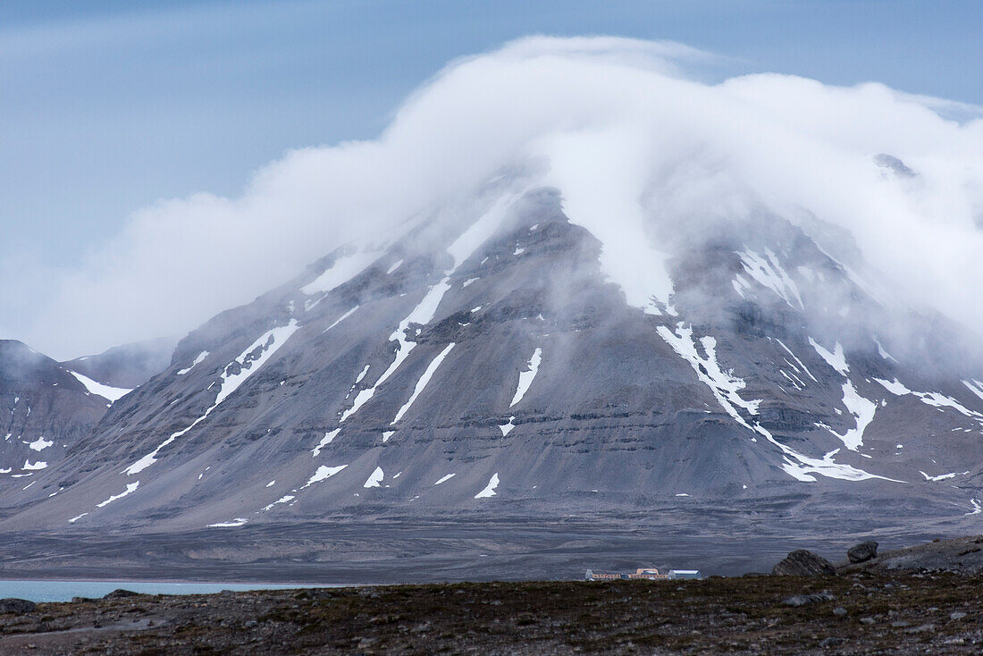 Clouds are lingering on one of the summits behind Ny-Ålesund on the southern shore of the Kongsfjord, Spitsbergen, Svalbard, Norway
