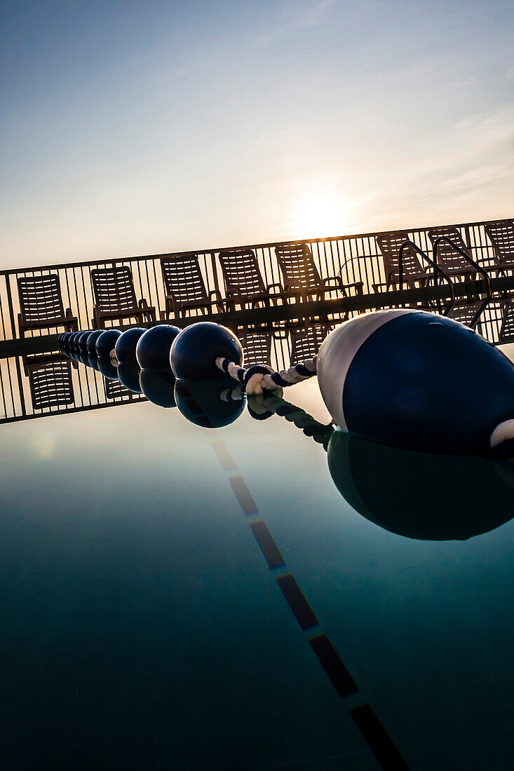 Pool with stop rope and deck chairs in the background against the light of the sunrise, Daytona Beach, Florida, USA