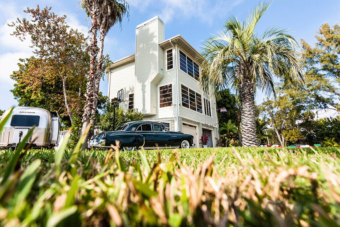 Ein alter schwarzer Cadillac und ein alter silbriger Airstream Wohnwagen vor einem typischen Florida Wohnhaus mit Palmen, Miami Beach, Miami, Florida, USA