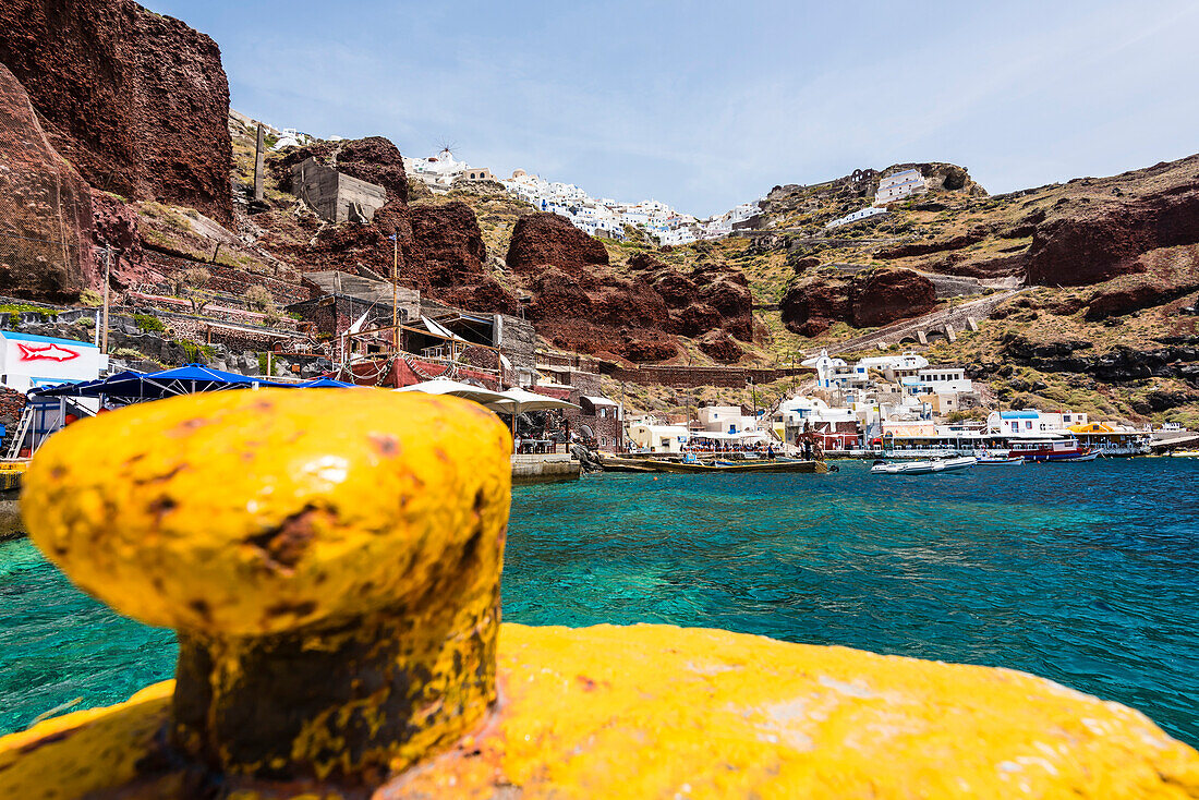Hafen von Amoudi Bay mit Blick auf die Steilküste und das Dorf mit der Windmühle und den traditionell gebauten Häusern, Oia, Kykladen, Santorini, Griechenland