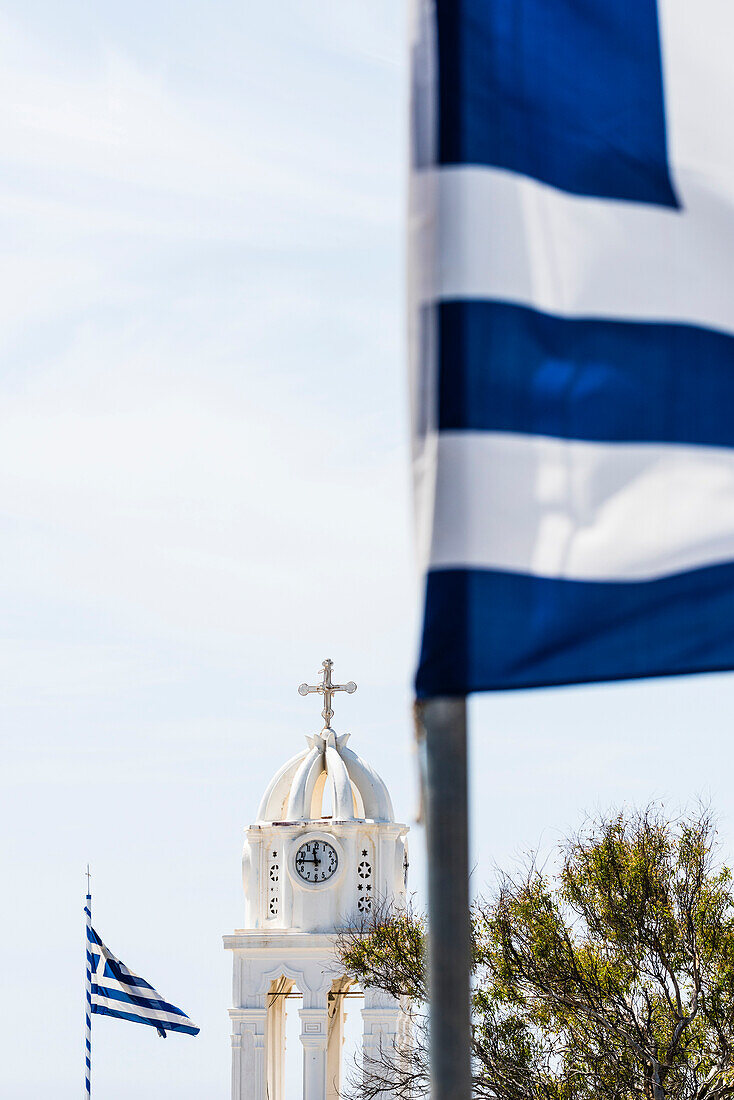 Bell tower of the church Isodia tis Panagias framed of two national flags, Megalochori, Cyclades, Santorini, Greece