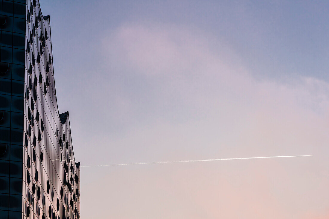 Die weltweit einzigartigen sphärisch gebogenen Glasscheiben des Konzerthauses Elbphilharmonie, mit dem Licht vom Sonnenaufgang, Hafencity, Hamburg, Deutschland