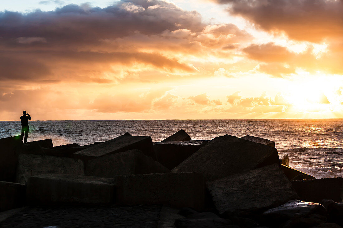 Mann auf der Küstenbefestigung beim Fotografieren vom Sonnenuntergang, Tazacorte, La Palma, Kanarische Inseln, Spanien
