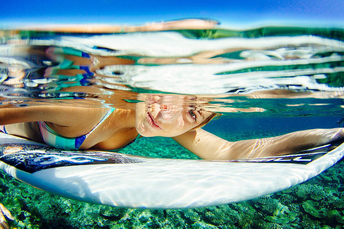 Underwater portrait of professional surfer Lucia Marti??o with her surfboard