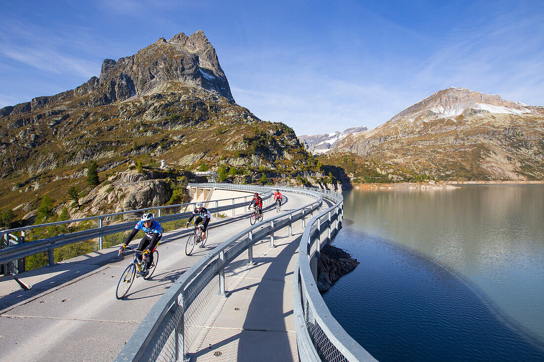 Four road bikers on the dam of the Emosson reservoir lake in the Alps on the border of France and Switzerland. It is an early morning training session of the local cyclists. The climb from Martigny to Finhaut will be stage 17 of the 2016 Tour de France on
