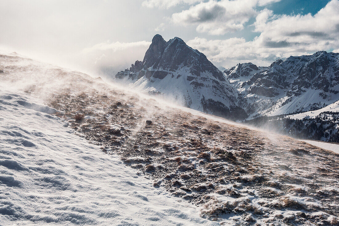 Snow blowing on top of the Gabler mountain,the Peitlerkofel in the background, Dolomites, Unesco world heritage, Italy