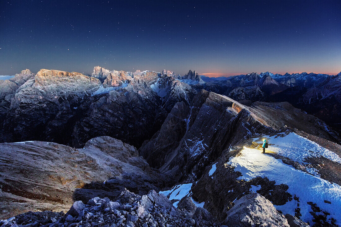 Hiker standing on top of Duerrenstein after sunset, panoramic view in direction to the Tre Cime di Lavaredo, Sexten Dolomites, Unesco world heritage, Italy