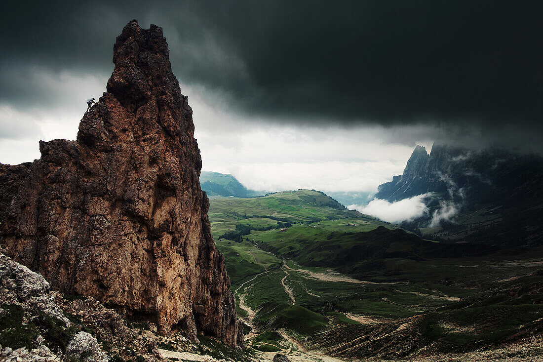 Wanderer klettert auf Felsbrocken am Fuße der Rosszähne, Schlerngruppe, Im Hintergrund die Seiser Alm, Südtirol, Italien