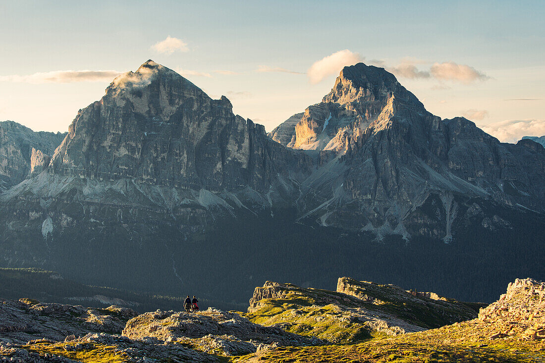 Two hikers on their way back from a hike in the area of Croda da Lago mountain, Bellunesi Dolomites, Unesco world heritage, In the background the Falzarego mountain pass and the iconic Tofane mountain, Italy