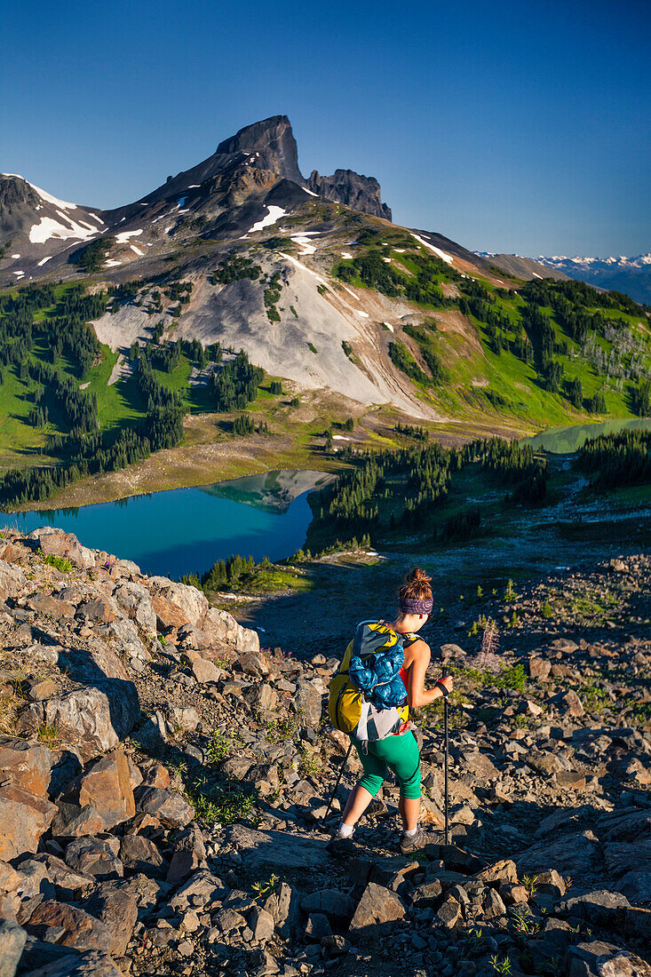 A young woman backpacking on the Panorama Ridge Trail with Black Tusk Mountain in the background in Garibaldi Provincial Park, British Columbia, Canada.