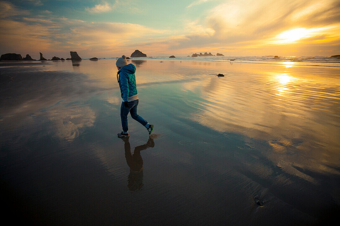 A young woman walks along Bandon Beach, Oregon.