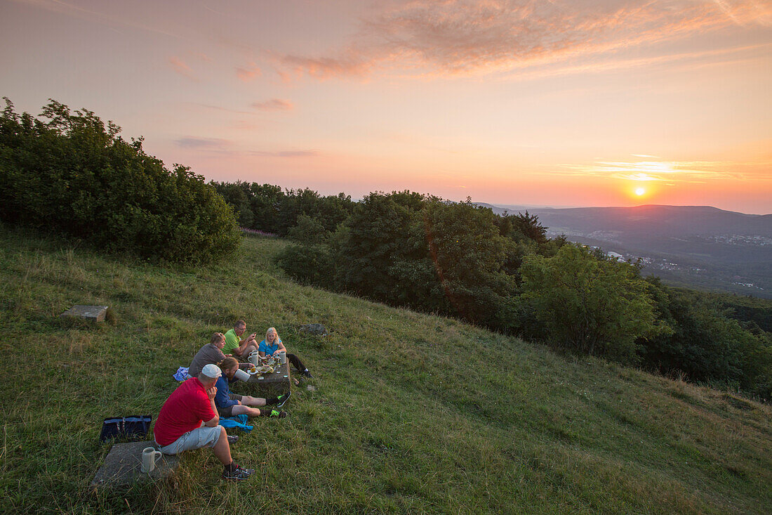 Pilger aus Würzburg genießen ein Picknick am Kreuzberg nach ihrer Pilgerwanderung auf dem Fränkischen Marienweg bei Sonnenuntergang, nahe Bischofsheim, Rhön, Bayern, Deutschland