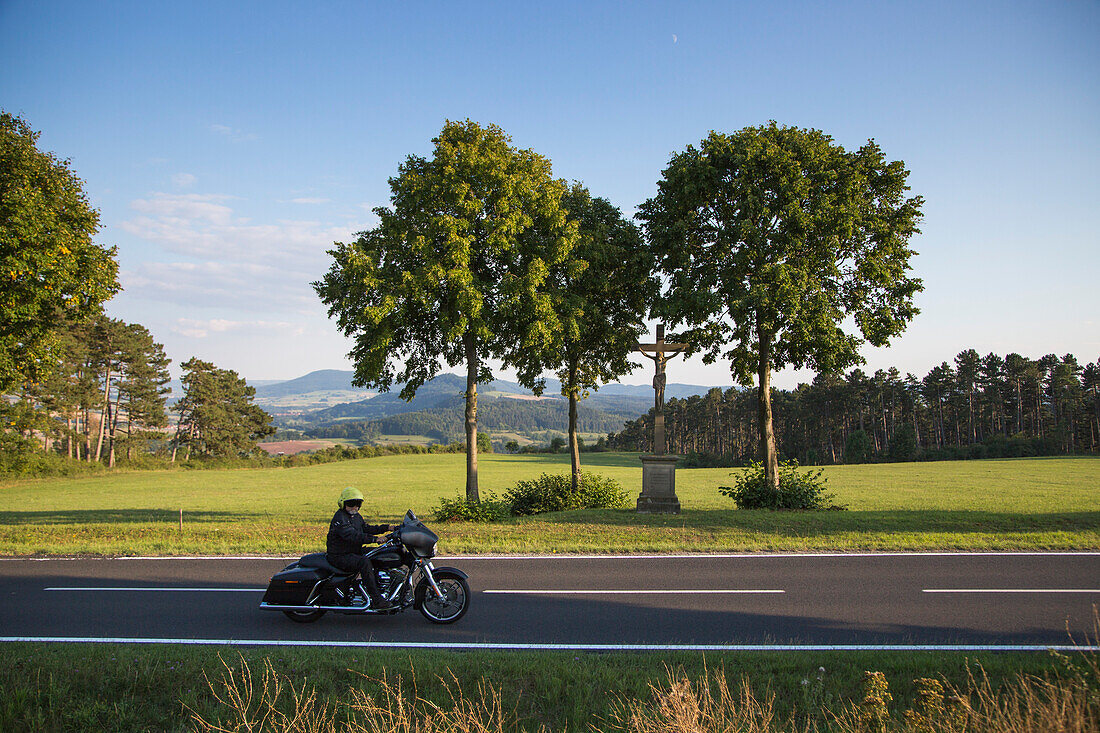 Motorradfahrer fährt eine Harley-Davidson auf der Straße zur Gedenkstätte Point Alpha, nahe Geisa, Rhön, Thüringen, Deutschland