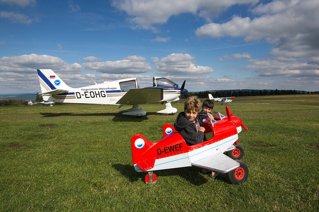 Young boys in toy airplanes at Kinderflugplatz adjacent to Flugplatz Wasserkuppe air field