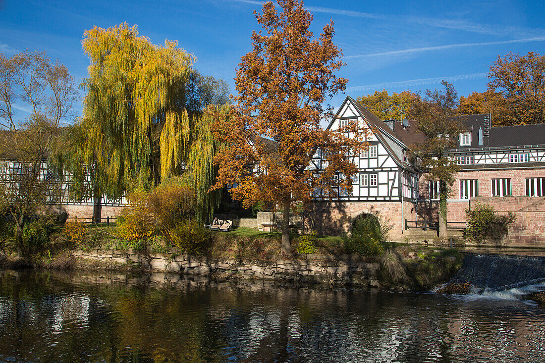 Neumühle Romantik Hotel along Fränkische Saale river and trees with autumn foliage