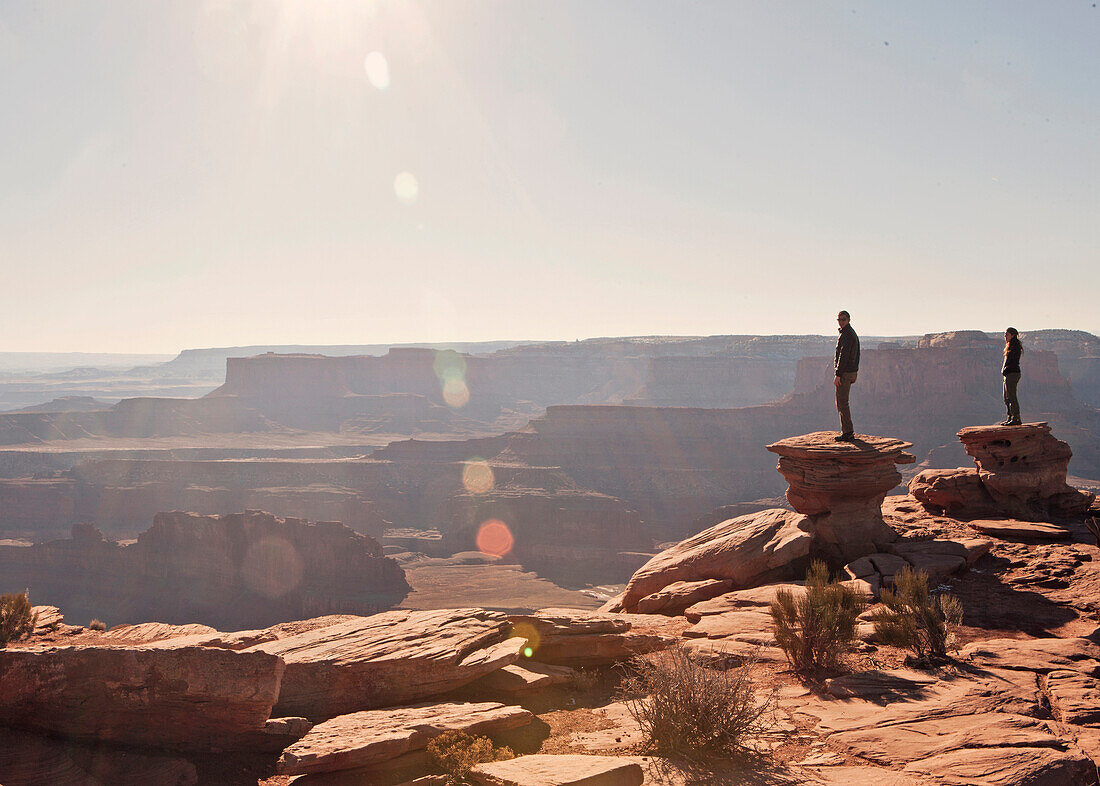 Two figures stand at the canyon's edge, Deadhorse Point State Park, Utah.