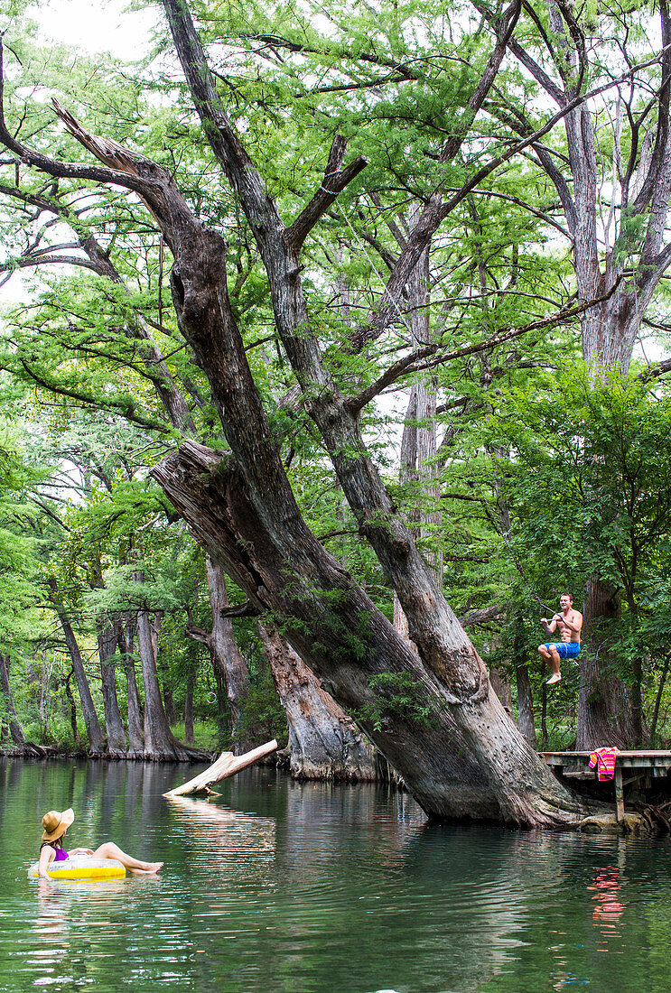 The Blue Hole in Wimberley, Texas is a popular destination for tourists and locals on hot summer days. The clear, cool water flows through cypress trees and offers a refuge from the Texas heat.