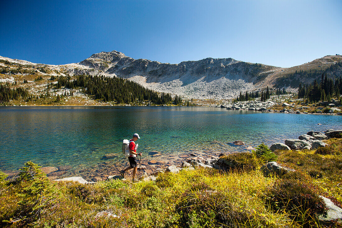 A ultralight backpacker hikes along the shore of Valentine Lake near Pemberton during a traverse of Cassiope and Saxifrage Mountains.