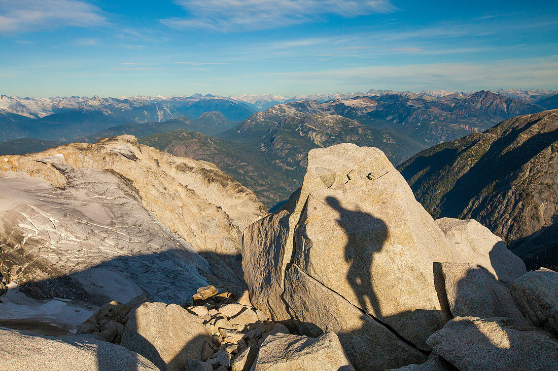 The shadow of a backpacker is projected on a large granite rock high in the rocky mountains of British Columbia, Canada.