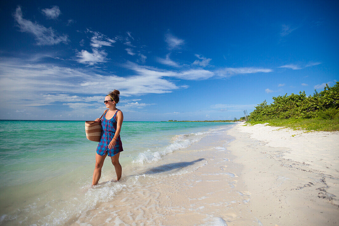 A young woman  walks the shoreline of a beach in Cayo Coco, Cuba.