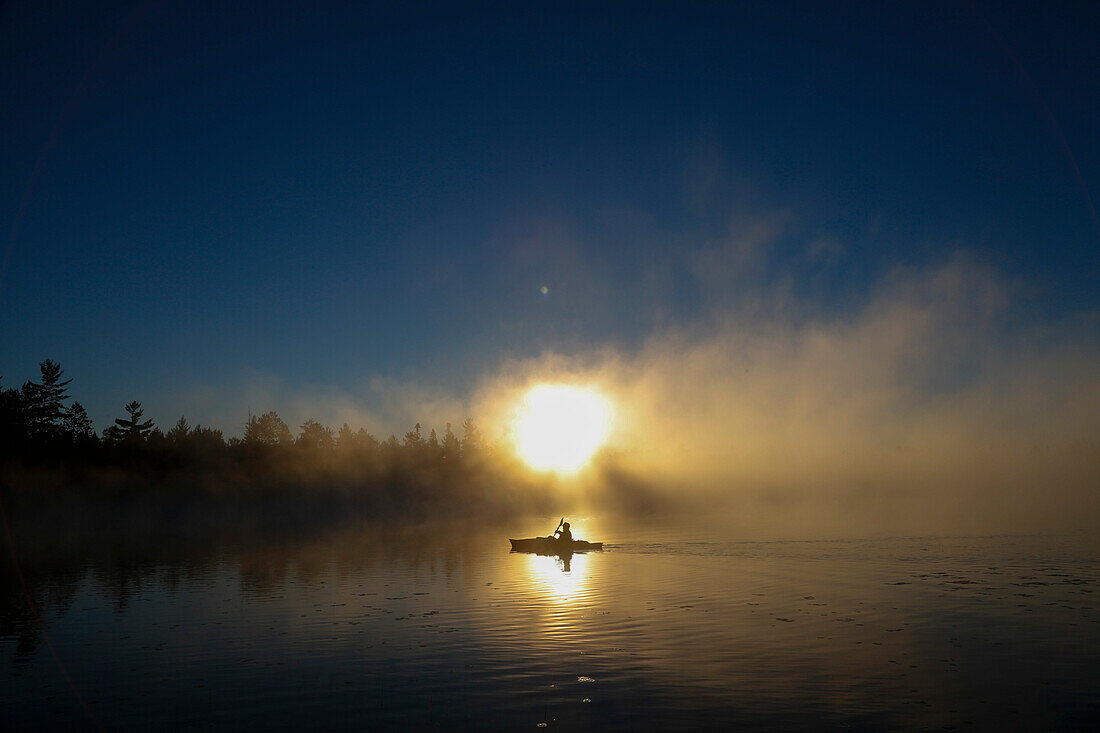 A kayaker enjoys the sunrise as steam rises from Lake Pleasant in Conover, Wisconsin on a brisk fall morning.