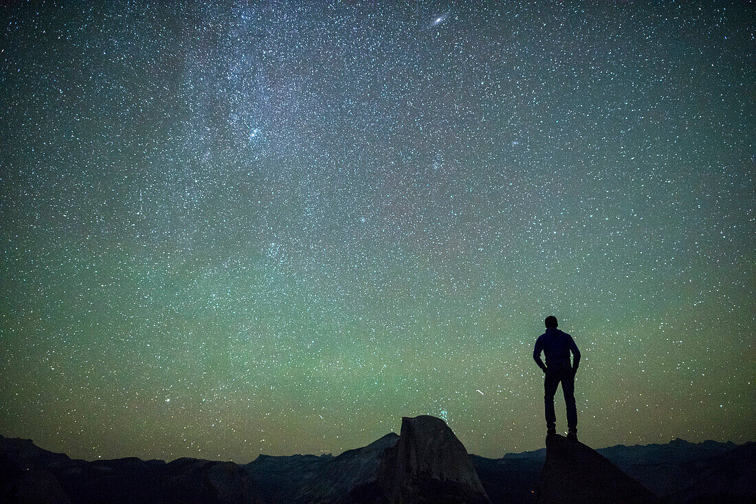 Man standing on a rock looking at Half Dome at night. Yosemite, CA, USA.