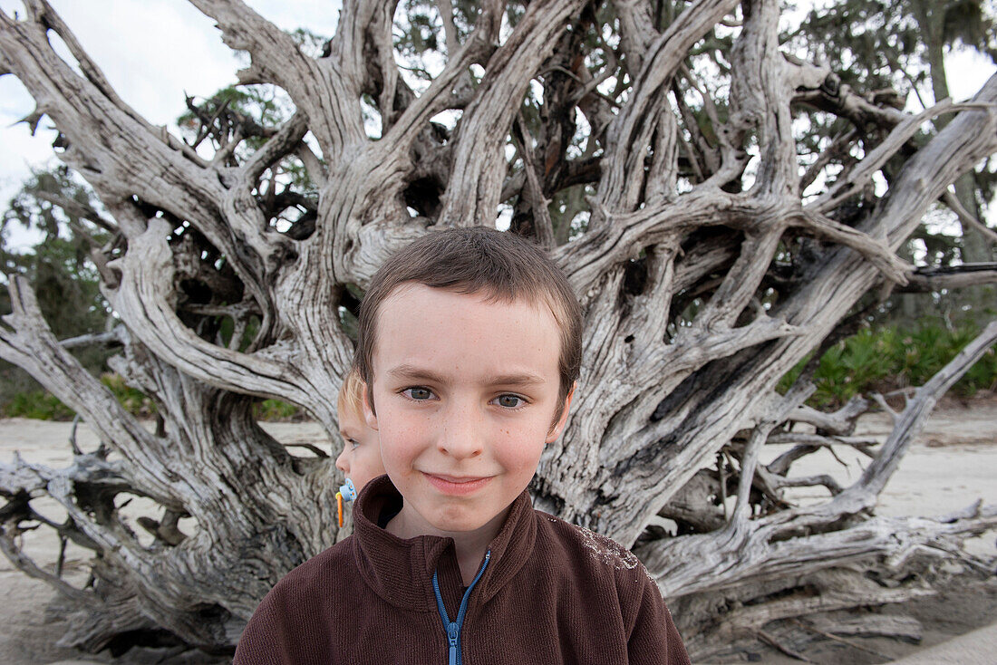 Boy in front of large piece of driftwood, portrait