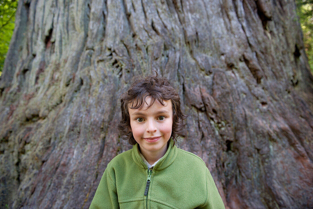 Boy in front of tree trunk, portrait