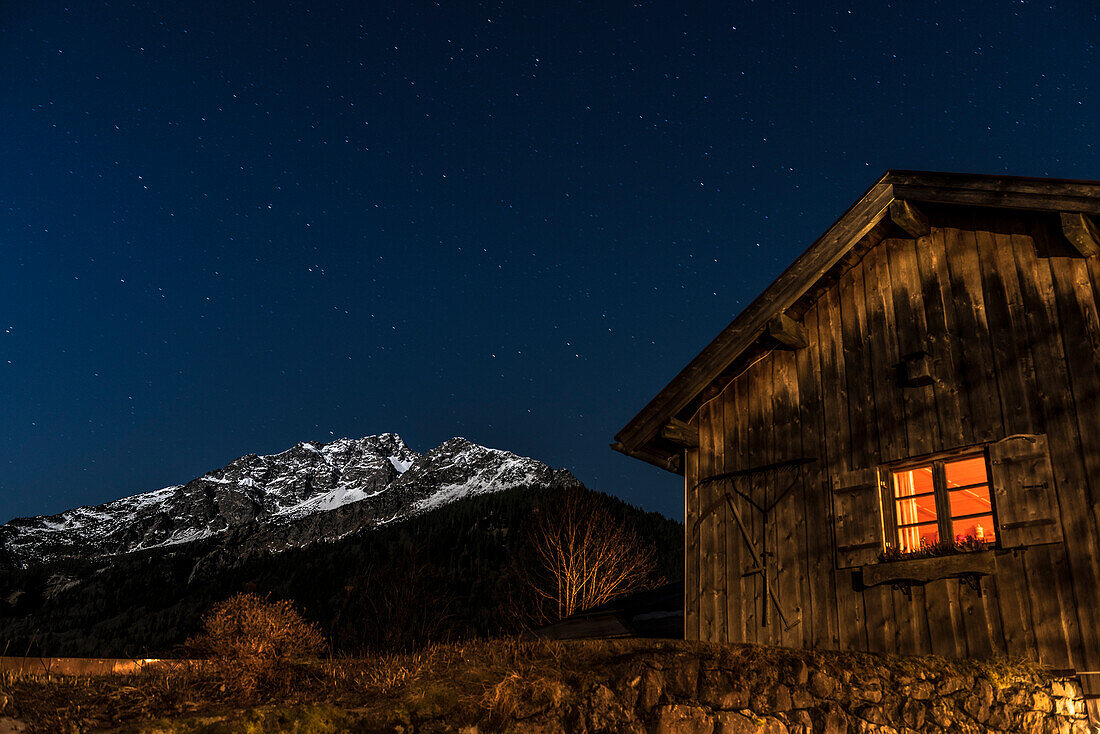 Bergpanorama bei Nacht mit Sternenhimmel in den deutschen Alpen vor einem Bauernhaus, Oberstdorf, Oberallgäu, Deutschland