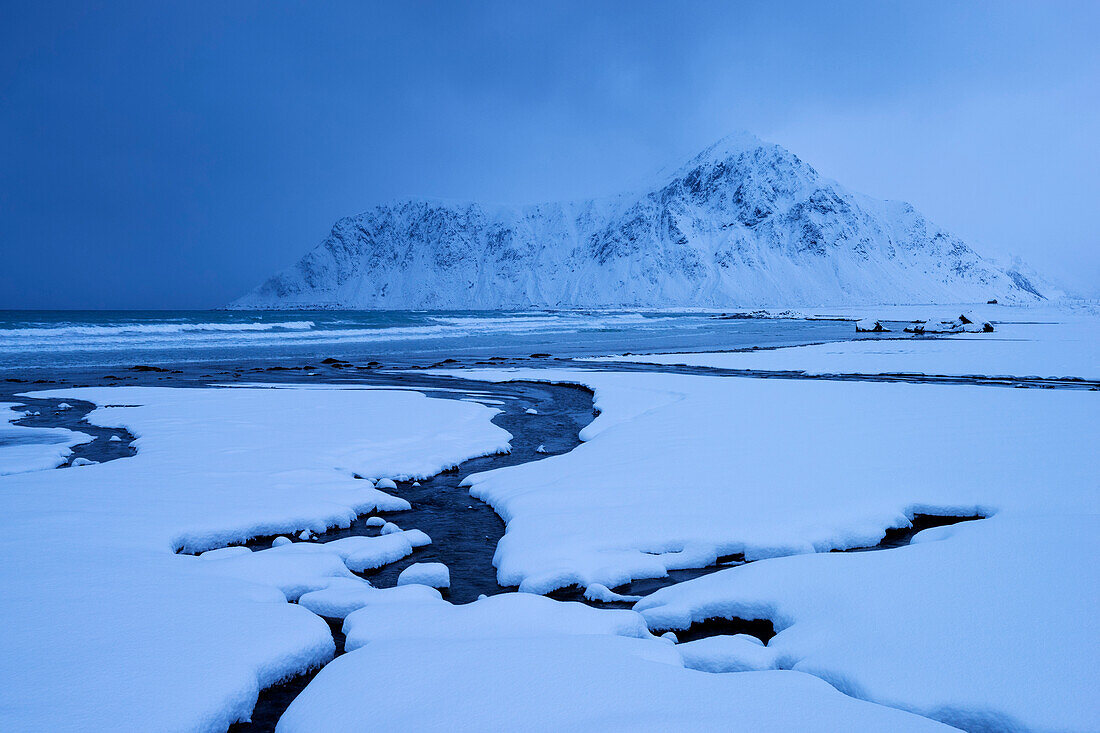 Verschneite Landschaft am Strand von Flakstad mit dem Gipfel des Hustinden (691 m) im Winter, Flakstadøya, Lofoten, Norwegen, Skandinavien