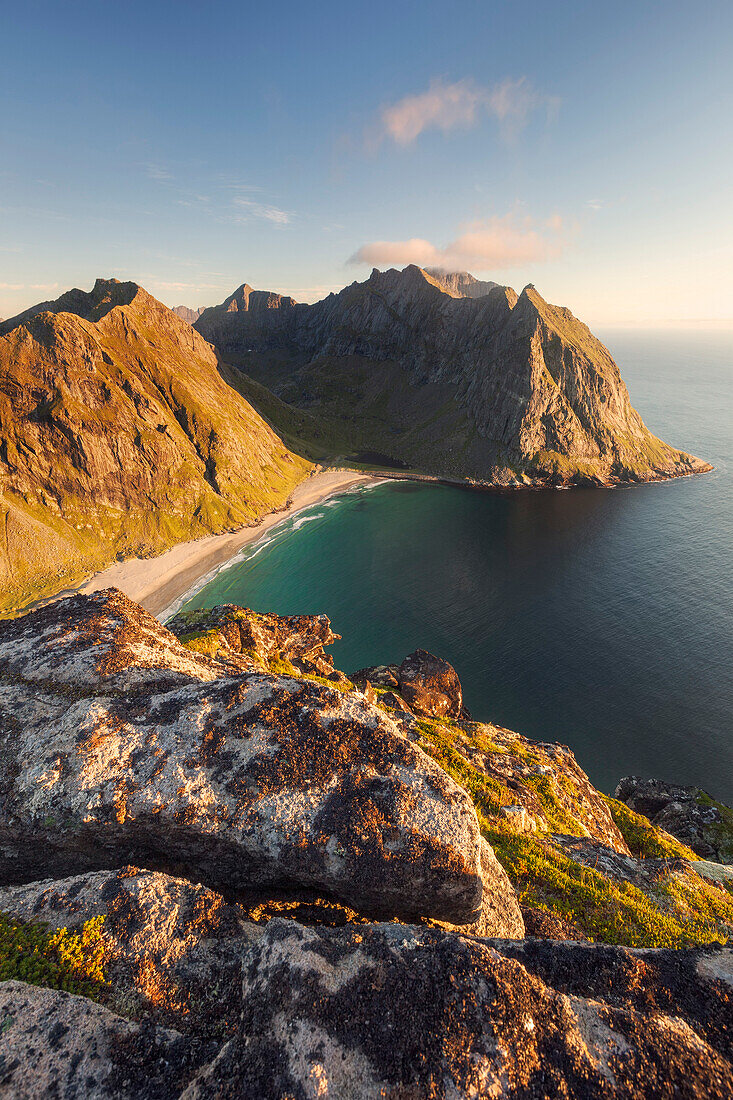 Wide view from top of Ryten to the sandy beach of Kvalvika bay and the surrounding mountains in the last evening light, Moskenesøy, Lofoten, Norway, Scandinavia