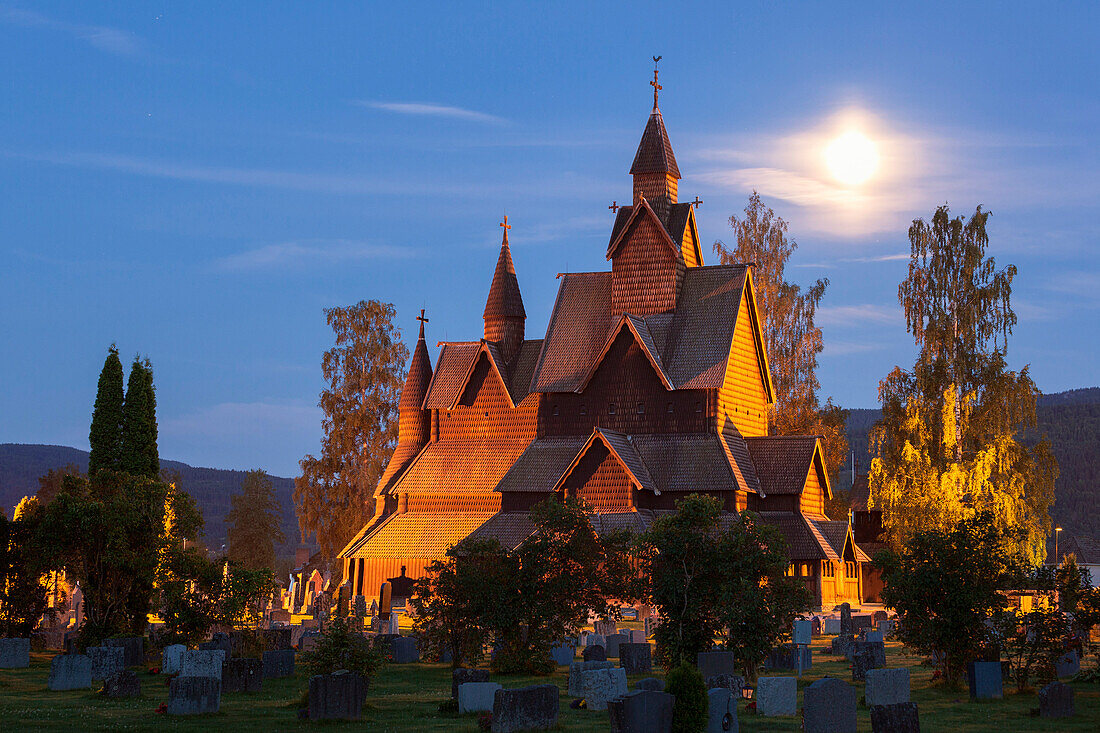 Heddal stave church with grave stones in a summer night with full moon, Notodden, Telemark, Norway, Scandinavia
