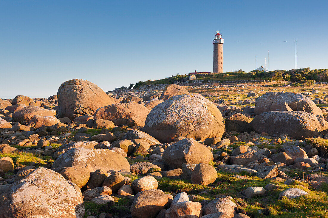 Lighthouse Lista fyr between large rocks in the morning sun, Farsund, Vest-Agder, Norway, Scandinavia
