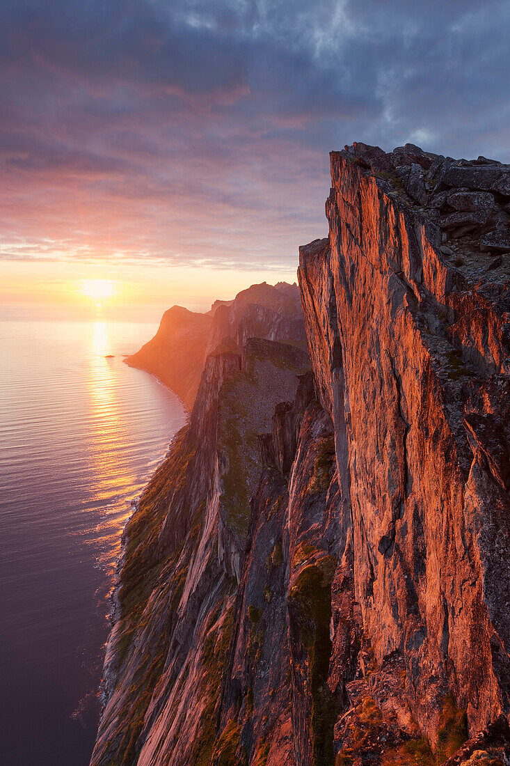 Überhängende Steilwand des Segla (640 m, auch als Preikestolen des Nordens bekannt) über dem Mefjorden zum Sonnenuntergang, Insel Senja, Fylke Troms, Norwegen, Skandinavien