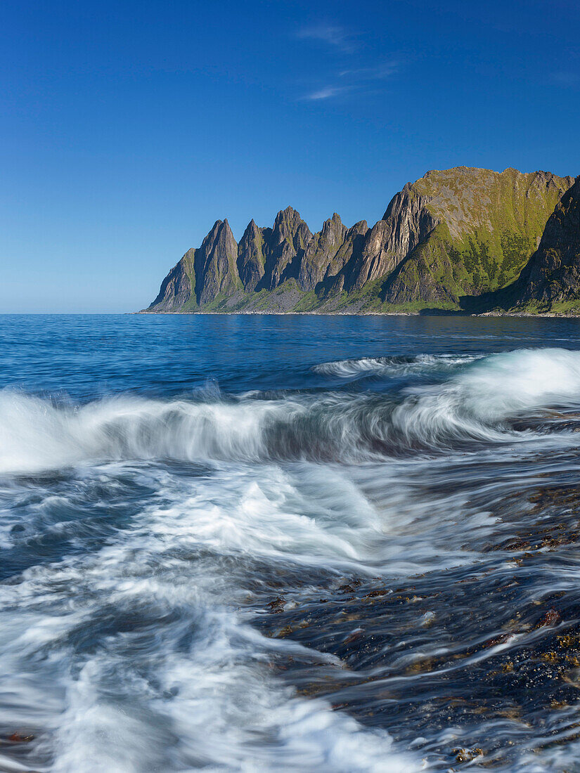 Okshornan Felsenspitzen am Ersfjordr in Nordnorwegen im Sommer mit Brandung im Vordergrund, Insel Senja, Fylke Troms, Norwegen, Skandinavien