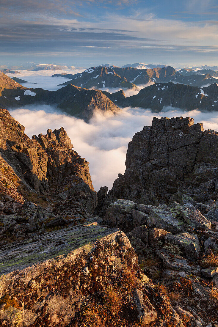 View from top of Skårasalen above the clouds to the surrounding peaks of the Sunnmøre Alps in the evening sun, Alesund, More og Romsdal Fylke, Norway, Scandinavia