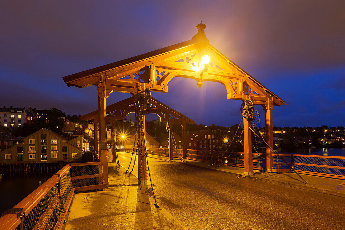 Blick auf die beleuchtete Holzbrücke Gamle Bybroen in der Altstadt von Trondheim in der Abenddämmerung, Trondheim, Sør-Trøndelag, Norwegen, Skandinavien