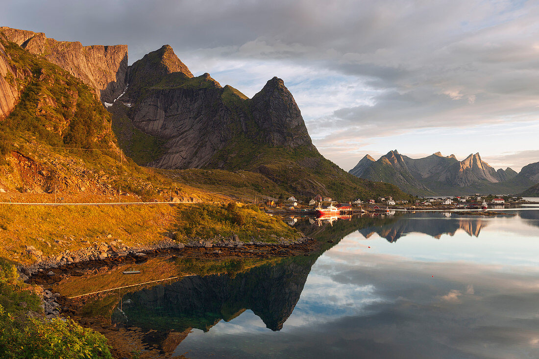 Meer und Felsen der Lofoteninsel Moskenesoy mit dem Fischerdorf Reine in der Morgensonne, Lofoten, Norwegen, Skandinavien