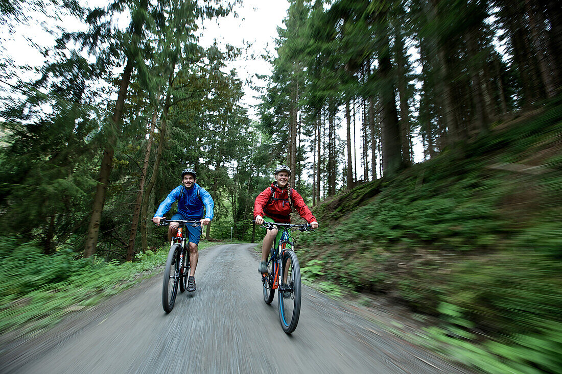Cyclists riding down a path through a forest