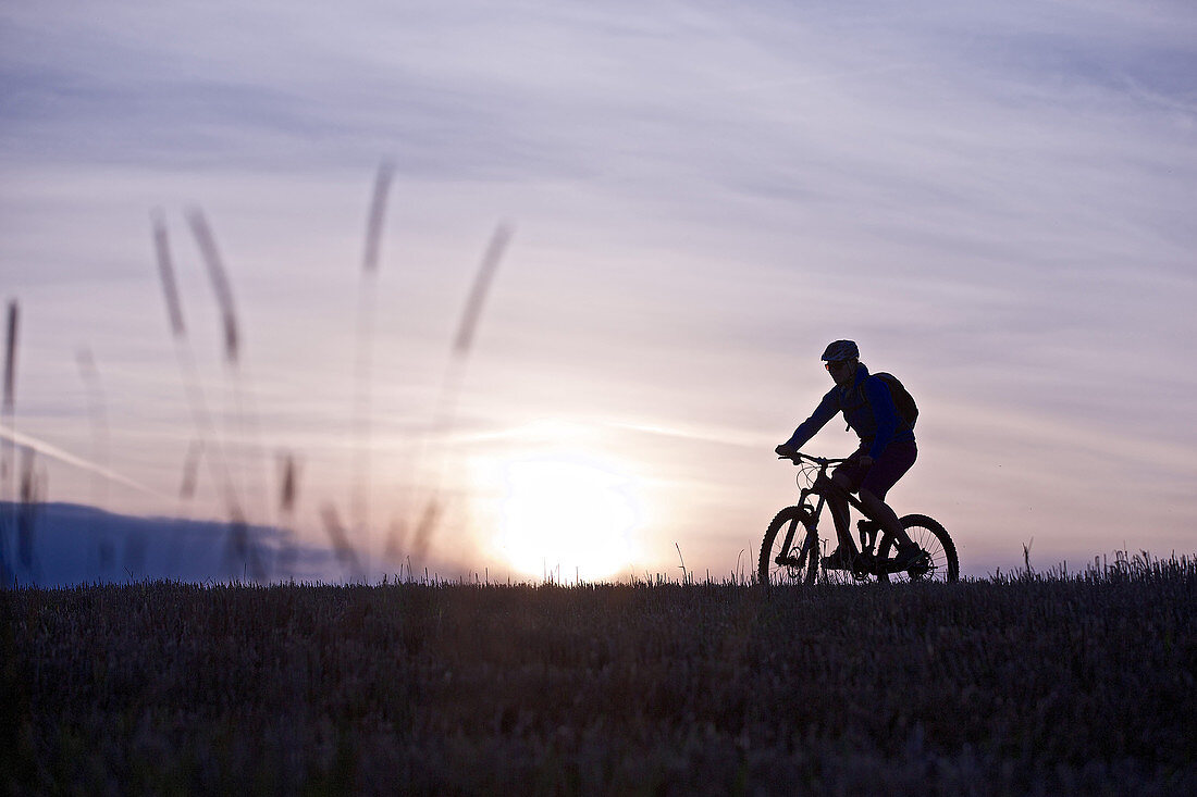 Young woman riding with her bike through a field