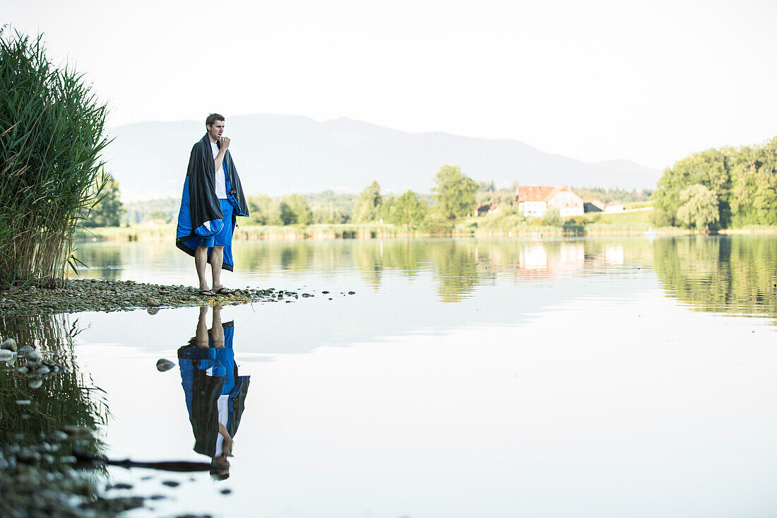 Junger Camper putzt sich die Zähne an einem See, Freilassing, Bayern, Deutschland