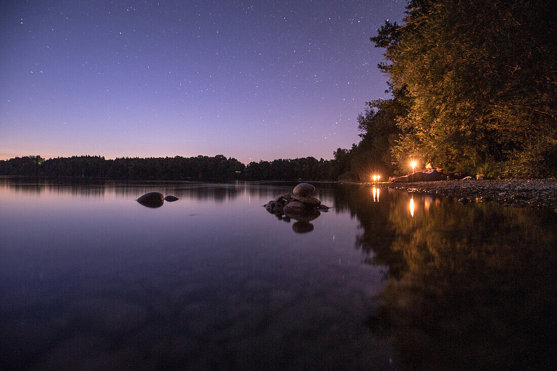 Junge Männer liegen an einem See bei Nacht, Freilassing, Bayern, Deutschland