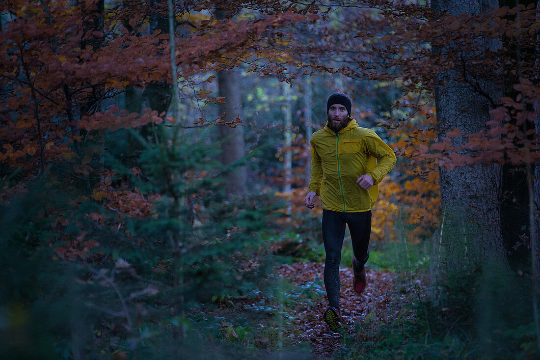 Junger Mann läuft auf einem Weg durch einen Wald, Allgäu, Bayern, Deutschland