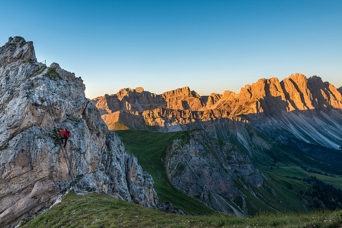Funes Valley, Dolomites, South Tyrol, Italy. Climber on the Via Ferrata GÃ¼nther Messner. In the background the Odle at Sunrise