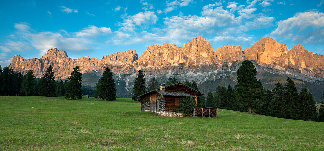 Carezza, Dolomites, South Tyrol, Italy. Mountain Hut in the pastures of Colbleggio. In the background the peaks of the Catinaccio group  Rosengarten